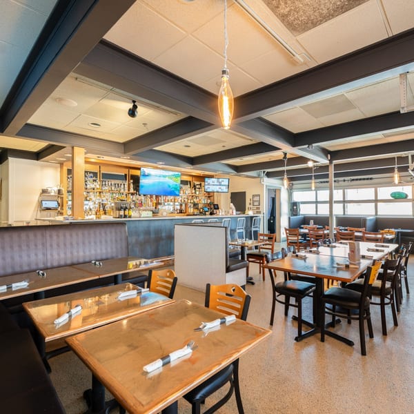 Interior of Mi Cava & Cocina restaurant with dining tables, booths, and a full bar area.