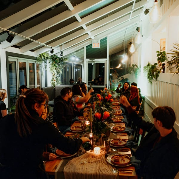 Guests enjoying a lively dinner party at Mi Cava & Cocina, with a long table adorned with flowers.