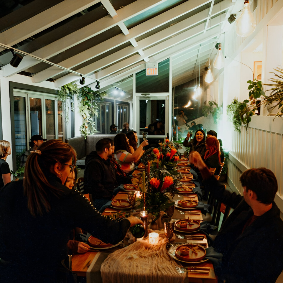 Guests enjoying a lively dinner party at Mi Cava & Cocina, with a long table adorned with flowers.