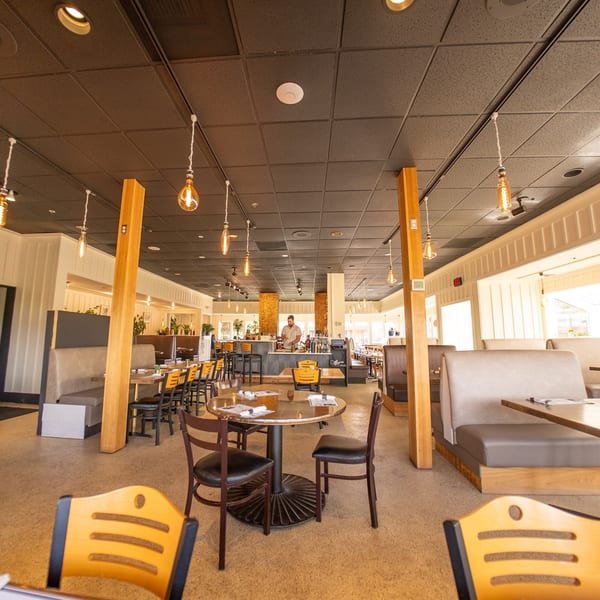 Spacious Mi Cava & Cocina dining room with tables, booths, and a bar area with a bartender.