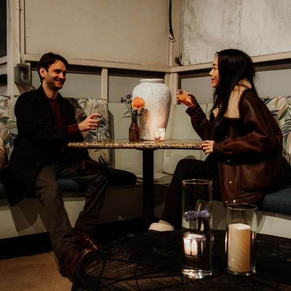 A man and woman clinking glasses at a table in Mi Cava & Cocina, with a vase of flowers.