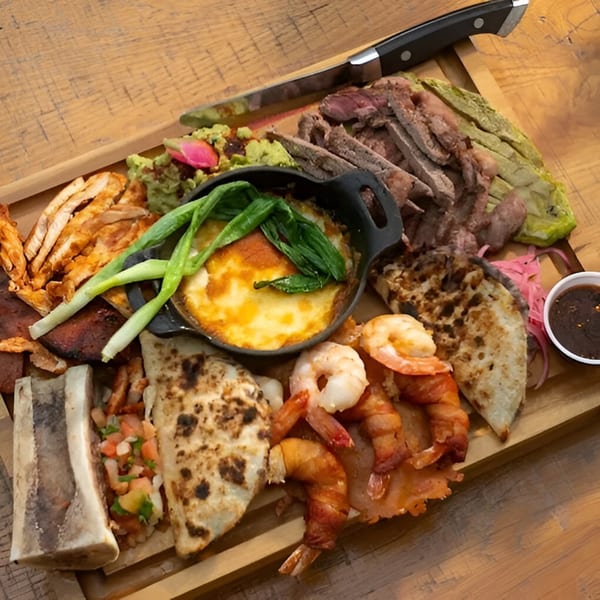 A large wooden platter of Mi Cava & Cocina's Mexican food, including steak, shrimp, and quesadillas.