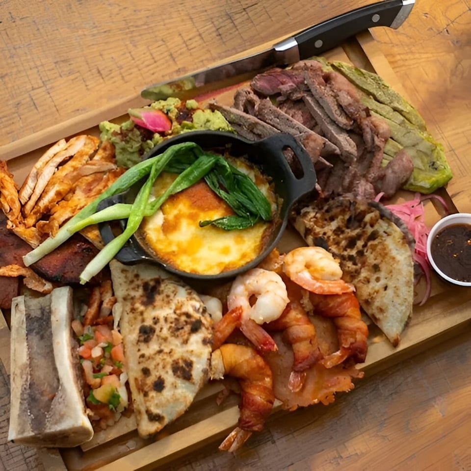 A large wooden platter of Mi Cava & Cocina's Mexican food, including steak, shrimp, and quesadillas.